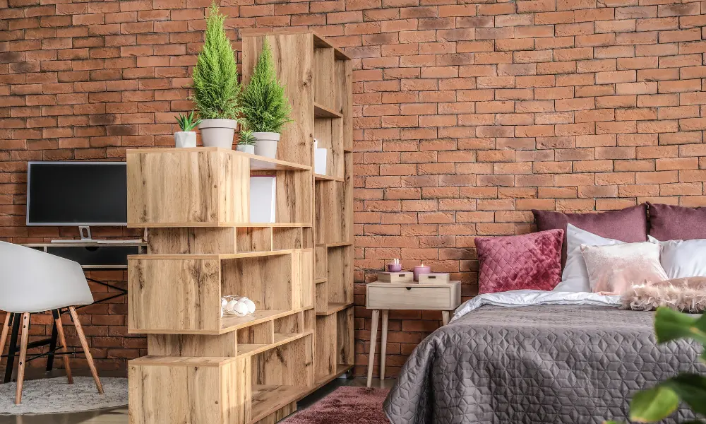 Integrated space with bed, wooden room divider shelf, and compact home office, ideal for small apartments.